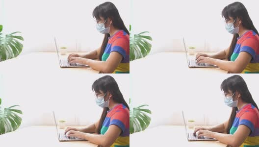 带口罩的亚洲商务女性在家庭办公室使用电脑，由于病毒危机在家里工作的商务人士高清在线视频素材下载