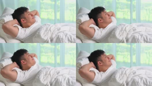 一个年轻的亚洲人躺在床上望着窗外。高清在线视频素材下载