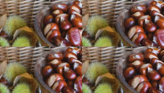 这是一个木碗里新鲜采摘的栗子的特写，背景是模糊的绿色刺猬。十月，栗子收获的季节。典型的秋季新鲜水果。高清在线视频素材下载