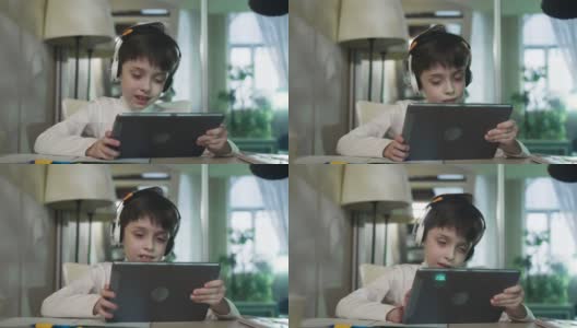 小男孩拿着平板电脑上网，在家玩游戏，听音乐。高清在线视频素材下载