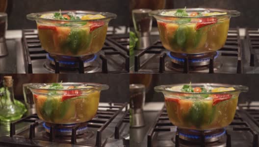 在烧开的水里煮填好的辣椒，放在炉子上一个透明的平底锅里，多利拍高清在线视频素材下载