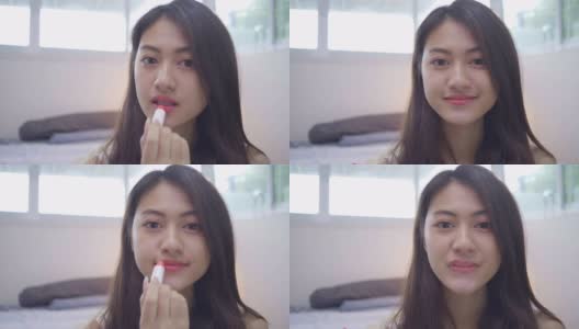 年轻的亚洲妇女在镜子前涂口红的美丽肖像高清在线视频素材下载