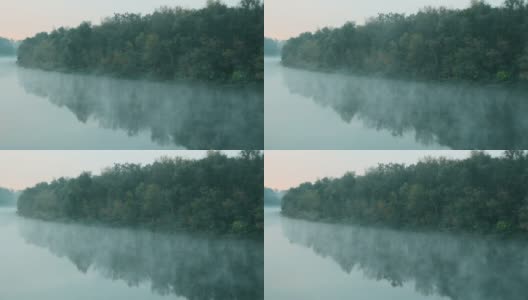 水上有烟。清晨拂晓时，雾漂浮在河上。绿色森林衬托下的美丽湖泊。水表面。大自然迷人的奇迹。文本的复制空间高清在线视频素材下载