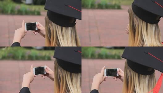 一名女毕业生用手机拍摄她的朋友，并竖起大拇指高清在线视频素材下载