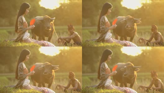 美丽的亚洲女人的肖像坐在傍晚与温暖的照明日落的田野。高清在线视频素材下载