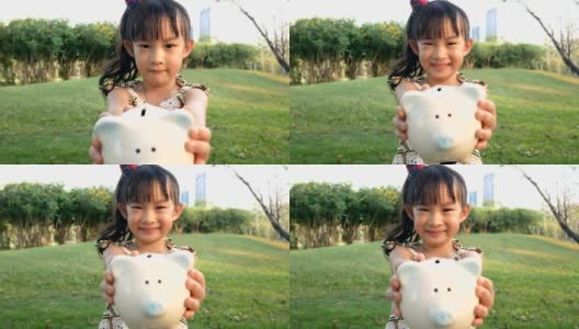 亚洲小孩抱着小猪储蓄罐迷人的微笑。高清在线视频素材下载