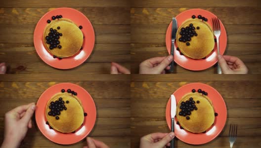 俯视图手把装有煎饼和浆果的盘子放在木桌上，推拉拍摄。高清在线视频素材下载