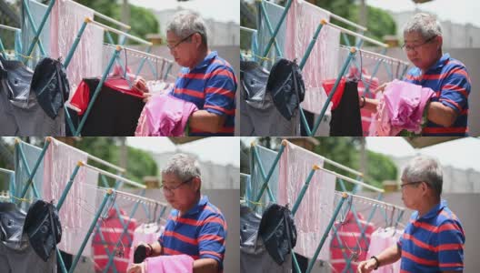 亚洲华人老人收集挂在前院清洗后的衣服高清在线视频素材下载