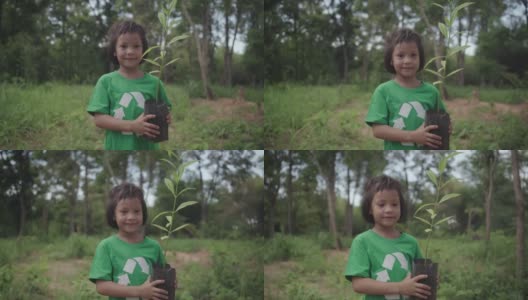 可爱的女孩站着，拿着一棵植物，她准备在森林里种一棵树。高清在线视频素材下载