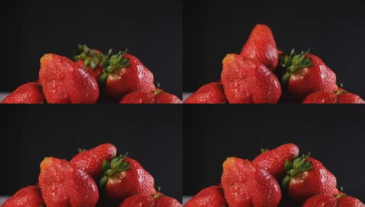 在黑色的背景上，一个草莓落在一把浆果上高清在线视频素材下载