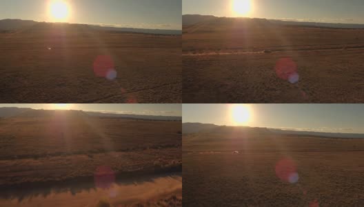航拍:金色日出时，一辆黑色SUV行驶在沙漠山谷尘土飞扬的道路上高清在线视频素材下载