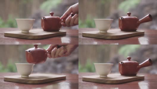 女子在后院的花园里用杯子倒绿茶高清在线视频素材下载
