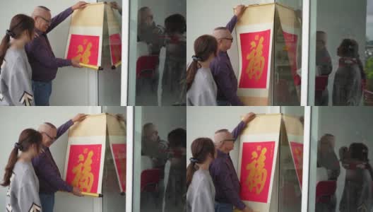 亚洲华人的爷爷和孙女正在贴春联，为即将到来的春节做准备高清在线视频素材下载