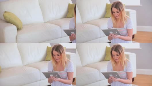 迷人的金发美女在用她的平板电脑高清在线视频素材下载