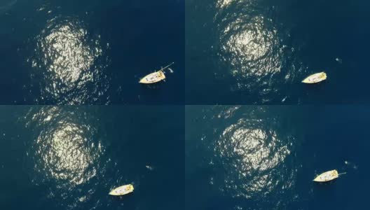 帆船鸟瞰图在蓝色的海洋与阳光闪烁和一个游泳者绕着船高清在线视频素材下载