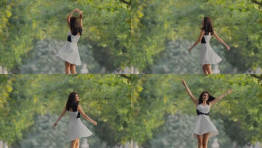 穿着裙子的黑发女孩在公园里快乐地打转，手在空中高清在线视频素材下载