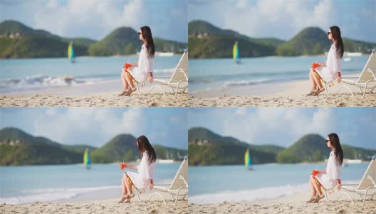 年轻女子在白色沙滩上喝着美味的鸡尾酒高清在线视频素材下载