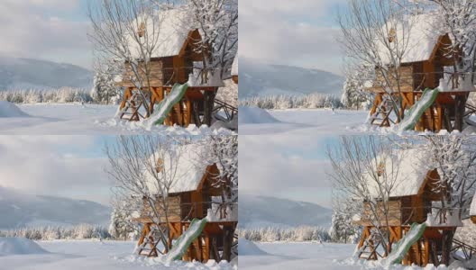 在阳光明媚的日子里，孩子们在白雪覆盖的山上玩耍的小房子高清在线视频素材下载