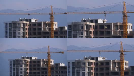 建筑工地上的塔式起重机在高层建筑中吊装重物高清在线视频素材下载