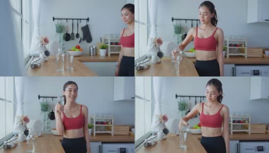 亚洲美女肖像在家里锻炼后喝水。年轻美丽口渴的运动女孩在家里的厨房为保健锻炼后喝一杯干净的天然矿物质高清在线视频素材下载
