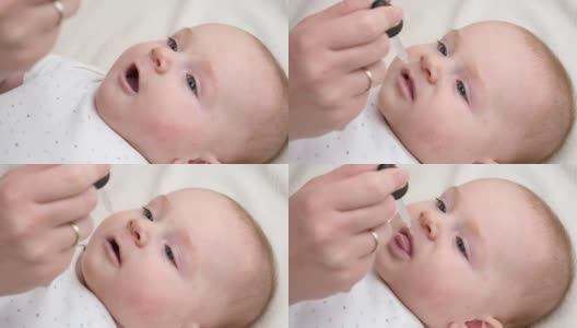 小男孩从滴管中摄取维生素D的特写。新生儿保健和疫苗接种的概念高清在线视频素材下载