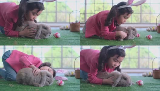 亚洲小女孩躺在兔子附近，也亲吻她的宠物在他们家的客厅表达爱和关心的情绪高清在线视频素材下载