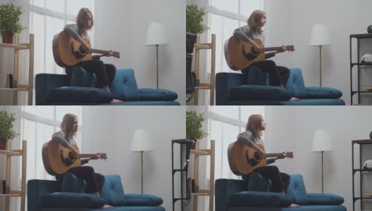 在一间白色的房间里，一个金发女孩在美丽的阳光下用原声吉他享受着美妙的旋律。长时间短。高清在线视频素材下载