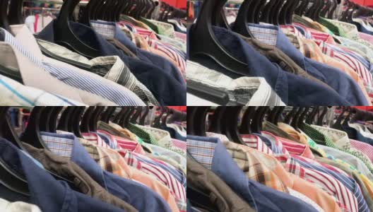 镜头沿着一排大量的彩色衬衫在二手商店的衣架移动。廉价购物的概念，黑色星期五高清在线视频素材下载