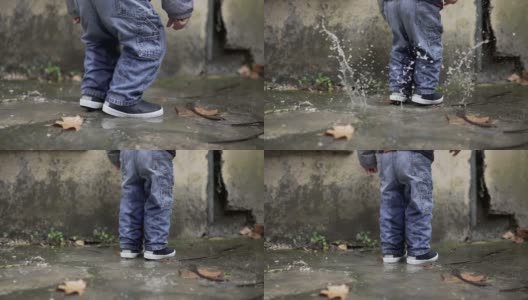孩子跳进水坑里。穿着靴子的幼童溅进水坑里高清在线视频素材下载