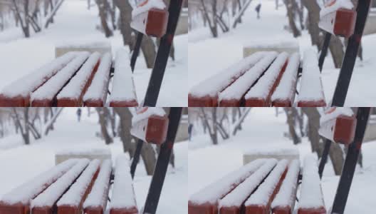 冬天的公园里下雪了，下雪的季节里，巷子里的人行道上积满了雪，积雪下空荡荡的长凳高清在线视频素材下载