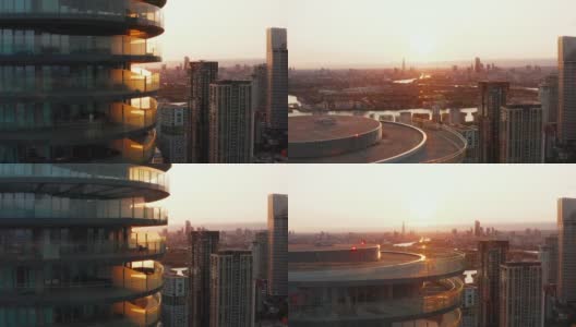 向上拍摄的高大的现代圆形公寓大楼，周围有一圈露台。夕阳映照下的城市景观。英国伦敦高清在线视频素材下载