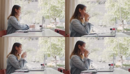 一个迷人的年轻女子坐在咖啡店里使用笔记本电脑的4k视频片段高清在线视频素材下载