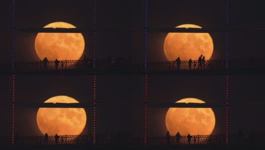 在升起的满月的背景下，桥上人影的剪影高清在线视频素材下载