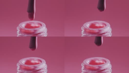 刷子正在从瓶子里取粉色指甲油。极端特写镜头高清在线视频素材下载