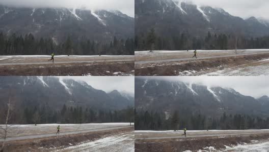 冬季，在积雪覆盖的山顶下，一名飞行员在一条穿越山谷的小道上奔跑高清在线视频素材下载