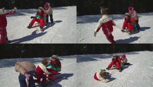 快乐的家庭在冬天的雪山森林里玩耍。妈妈和她的两个孩子在玩雪橇。他们笑了。高清在线视频素材下载