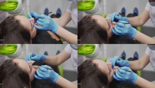 年轻的女牙医正在检查病人的牙齿。近距离观察女牙医的手在手套拿着仪器。牙齿健康和牙齿保健。高清在线视频素材下载