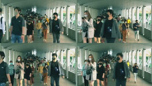 在泰国曼谷的崇诺寺BTS车站，下班高峰期，许多人戴着面具走在大桥上的慢镜头。高清在线视频素材下载