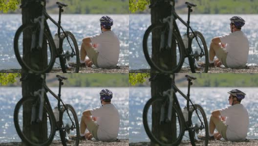 骑自行车的人坐在风景如画的湖边高清在线视频素材下载