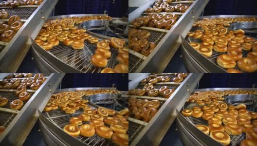 在面包房的工厂里制作新鲜又热又好吃的百吉饼-百吉饼在传送带上运输并分类。4K超高清视频全景运动。高清在线视频素材下载