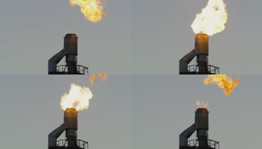 在灰色天空的映衬下，炼油厂里燃烧着的火炬高清在线视频素材下载