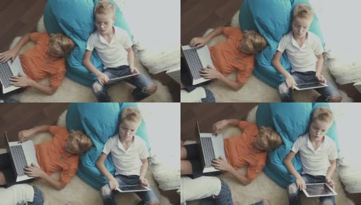 小男孩坐在家里的地板上使用电子产品高清在线视频素材下载