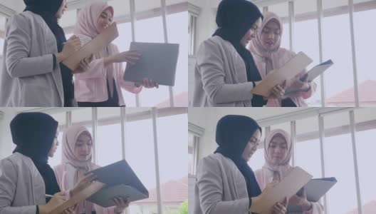 两位美丽的穆斯林女性办公室工作人员站在会议上讲话，并看着文件文件和握手祝贺他们的成功高清在线视频素材下载