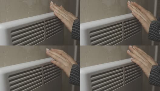 一个俄罗斯女人正在一个寒冷的房子散热器取暖自己，与供暖的问题，加热房间与一个电对流高清在线视频素材下载