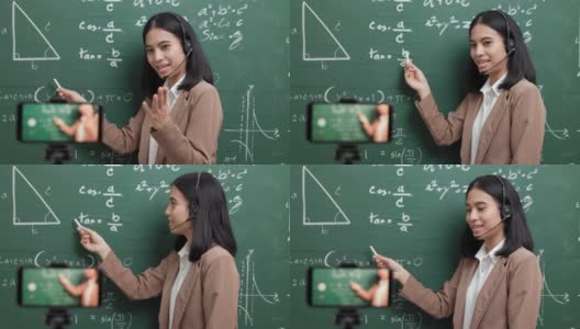 年轻的亚洲女教师站在摄像机和学生视频会议。女教师在课堂上通过智能手机在线课程直播培训数学。高清在线视频素材下载