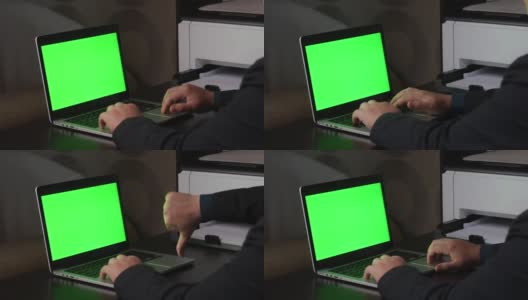 一名男子在一台绿色屏幕的笔记本电脑前工作。表示拇指向下的手势。Chromakey。高清在线视频素材下载