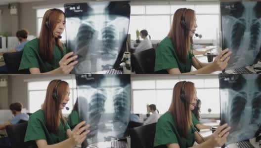 亚洲护士在呼叫中心办公室的电脑上对病人进行远程保健咨询。高清在线视频素材下载