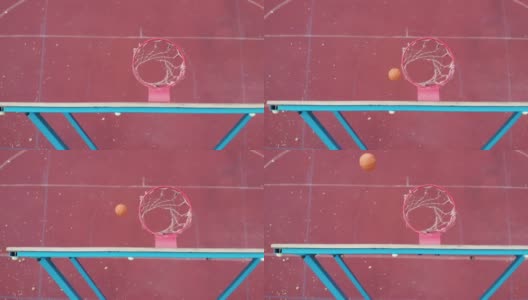 篮球篮板上方的顶角橙色球击中篮筐，在室外红色球场慢速动作中得分高清在线视频素材下载