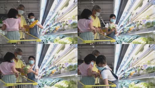 一个亚裔中国女孩和她的祖父和妹妹在超市的冷藏区买一些蔬菜高清在线视频素材下载