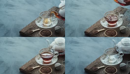 工艺泡茶，将热腾腾的茶水从茶壶倒进茶杯里，放在深色厨房餐桌背景的旧木板上，静物放松时光的深色心情风格。高清在线视频素材下载